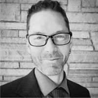 black and white image of a man with glasses smiling in a suit