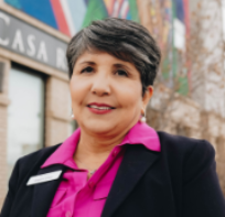 Woman with short grey hair smiling in a suit
